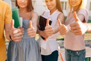 Group of happy students showing thumbs up Close-up